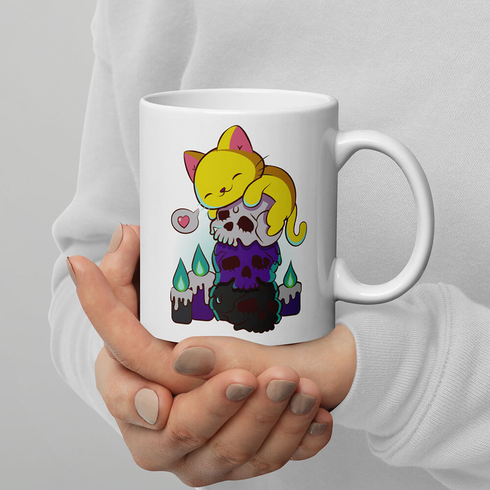 https://irenekohstudio.com/cdn/shop/files/Kawaii-Cat-on-Skulls-Nonbinary-Pride-Aesthetic-Mug-for-Enby_on-Hand.jpg?v=1684835633